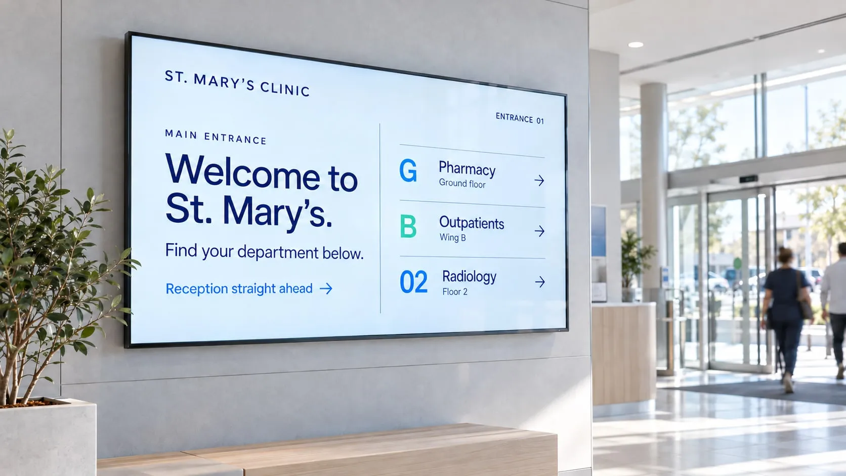 Clinic entrance with a large wall screen welcoming patients and pointing to the pharmacy, outpatients and radiology